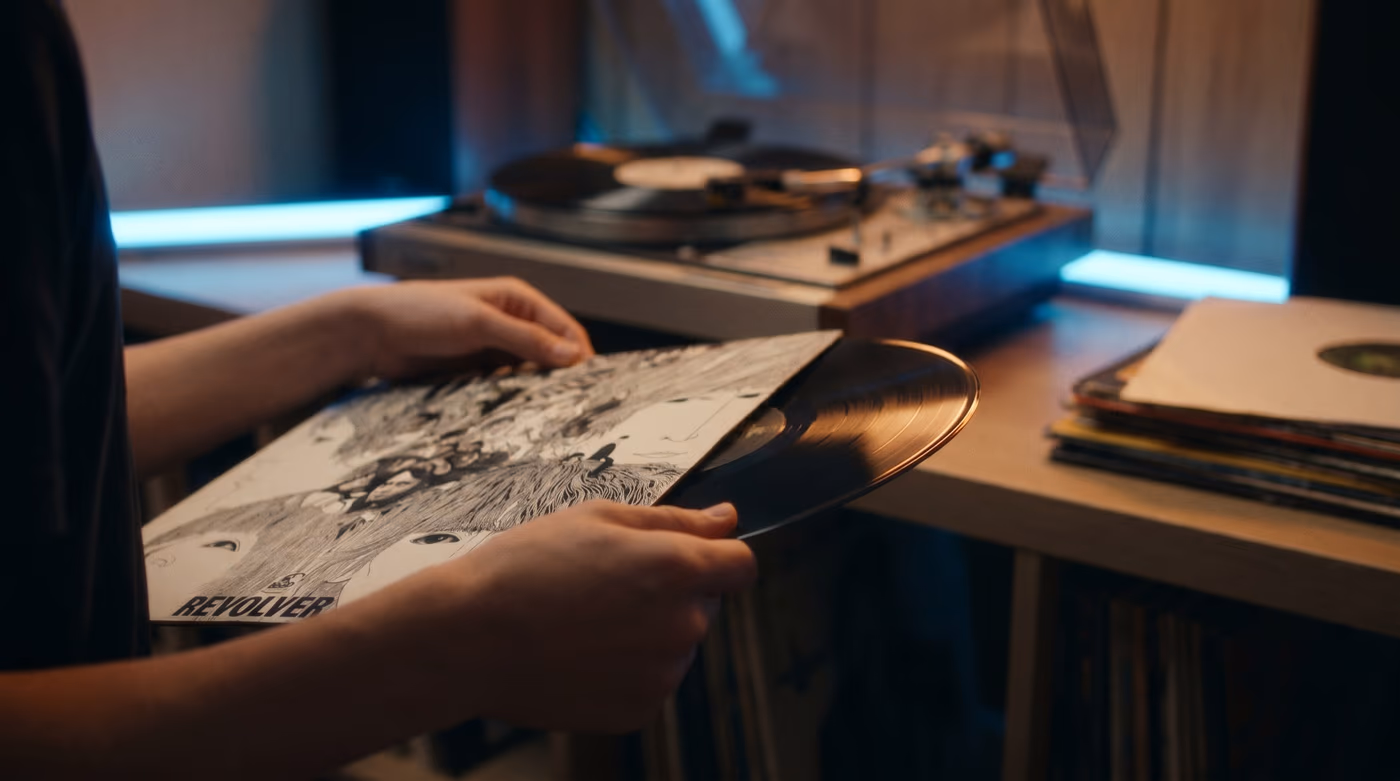 Mains tenant un vinyle sorti de sa pochette dans une chambre éclairée aux néons
