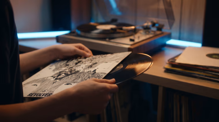 Mains tenant un vinyle sorti de sa pochette dans une chambre éclairée aux néons